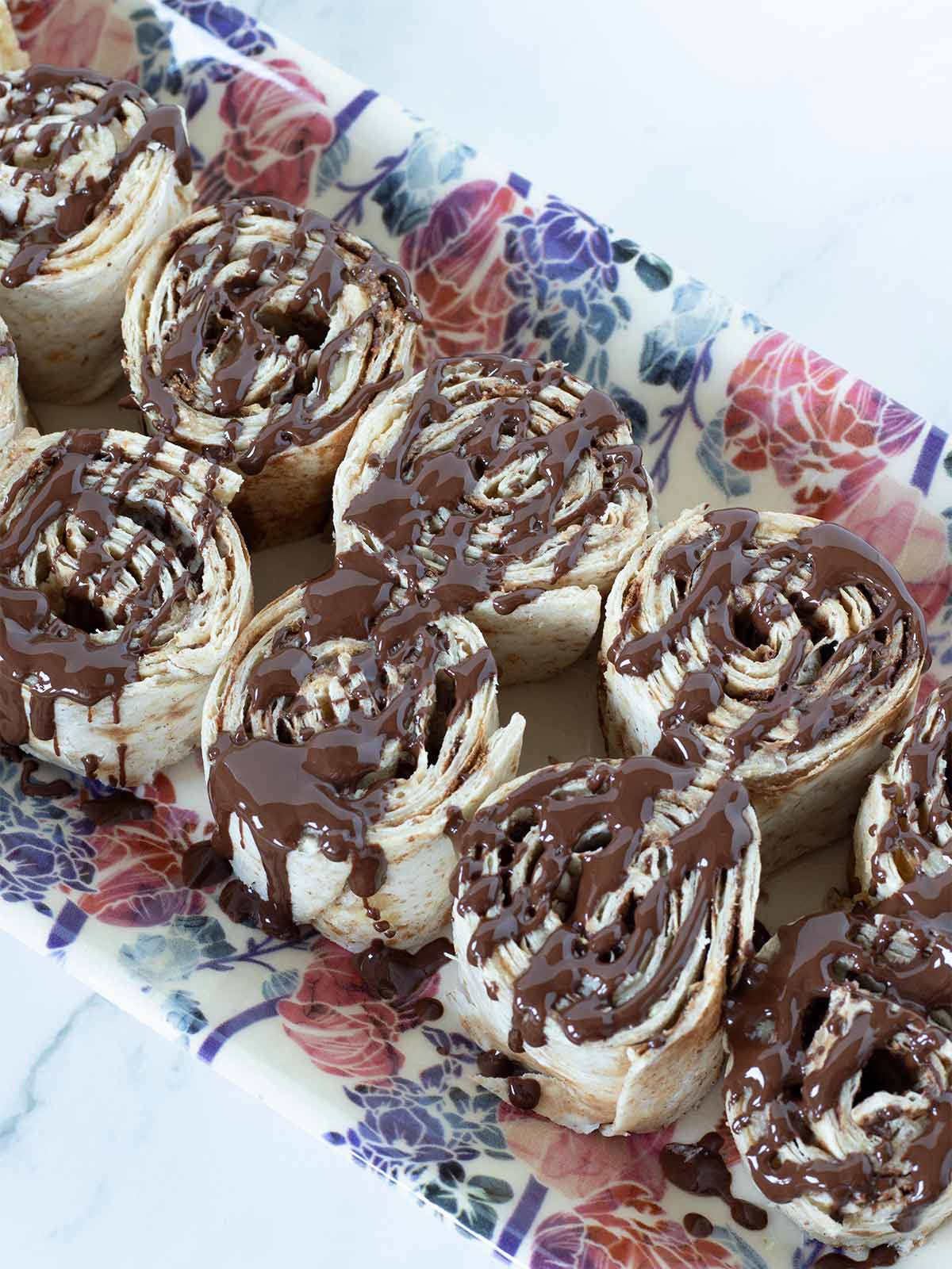 Sweet dessert tortilla roll up drizzled with melted chocolate.