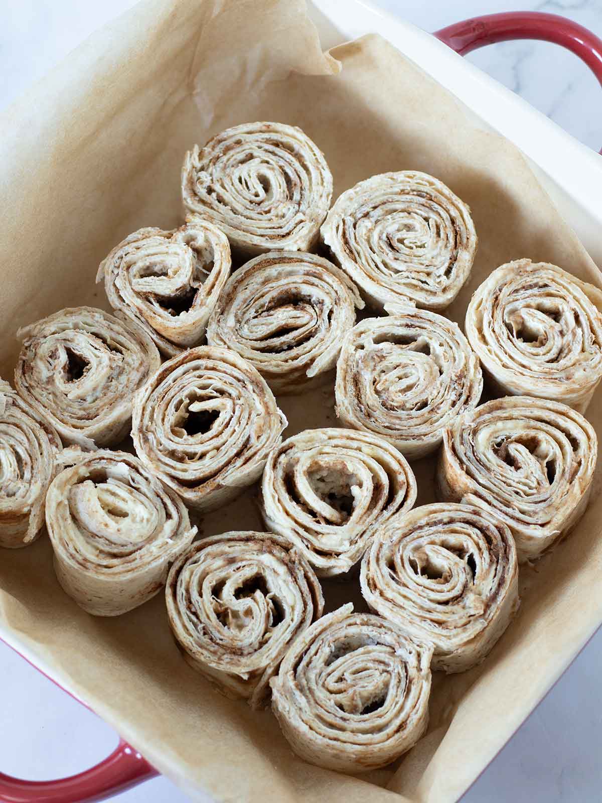 Mini tortilla cinnamon rolls in baking pan.