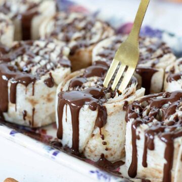 Tortilla cinnamon rolls with cream cheese and brown sugar drizzled with melted dark chocolate.