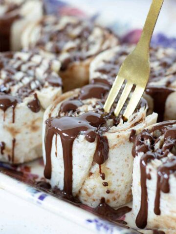 Tortilla cinnamon rolls with cream cheese and brown sugar drizzled with melted dark chocolate.