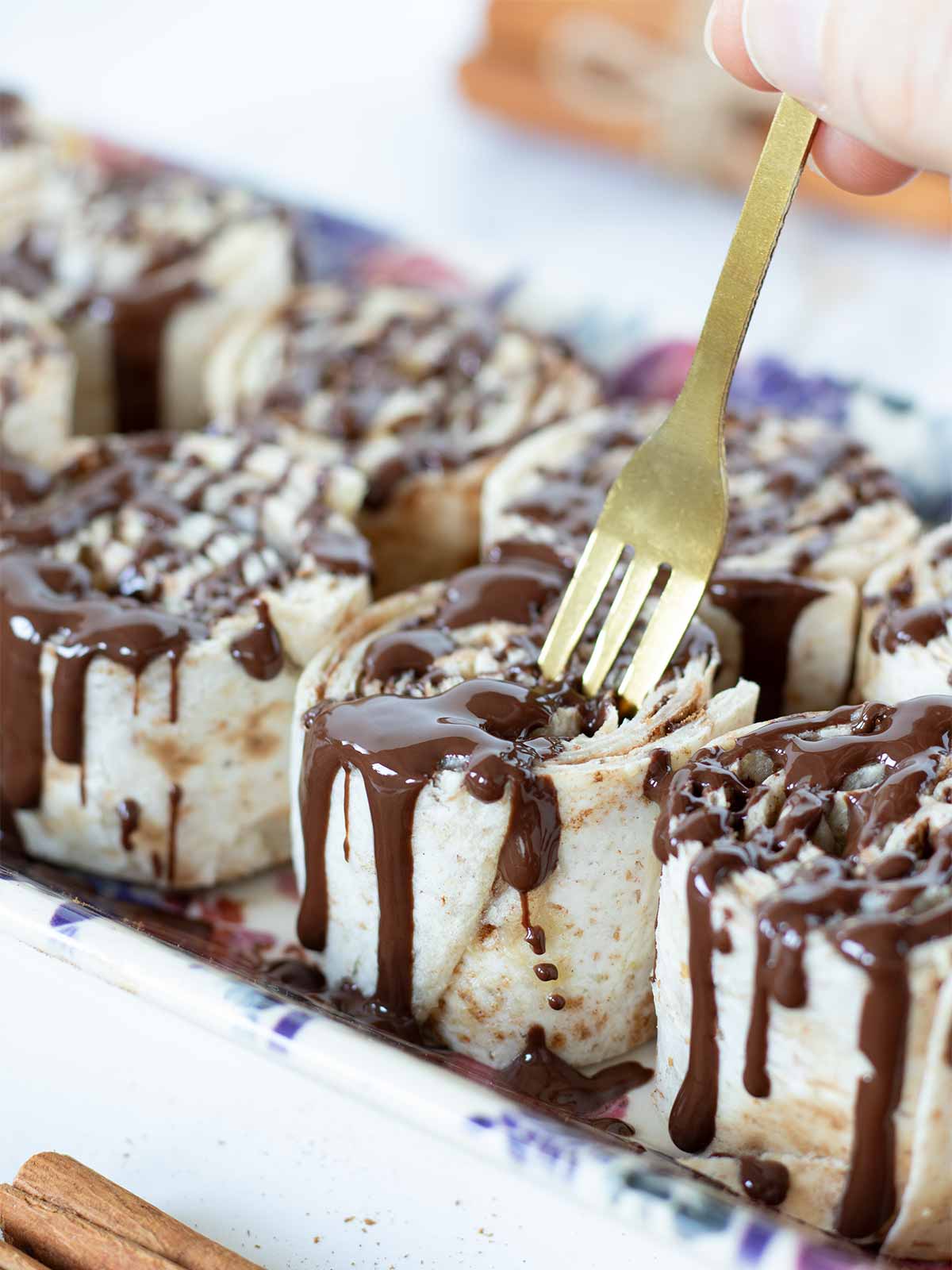 Tortilla cinnamon rolls with cream cheese and brown sugar drizzled with melted dark chocolate.