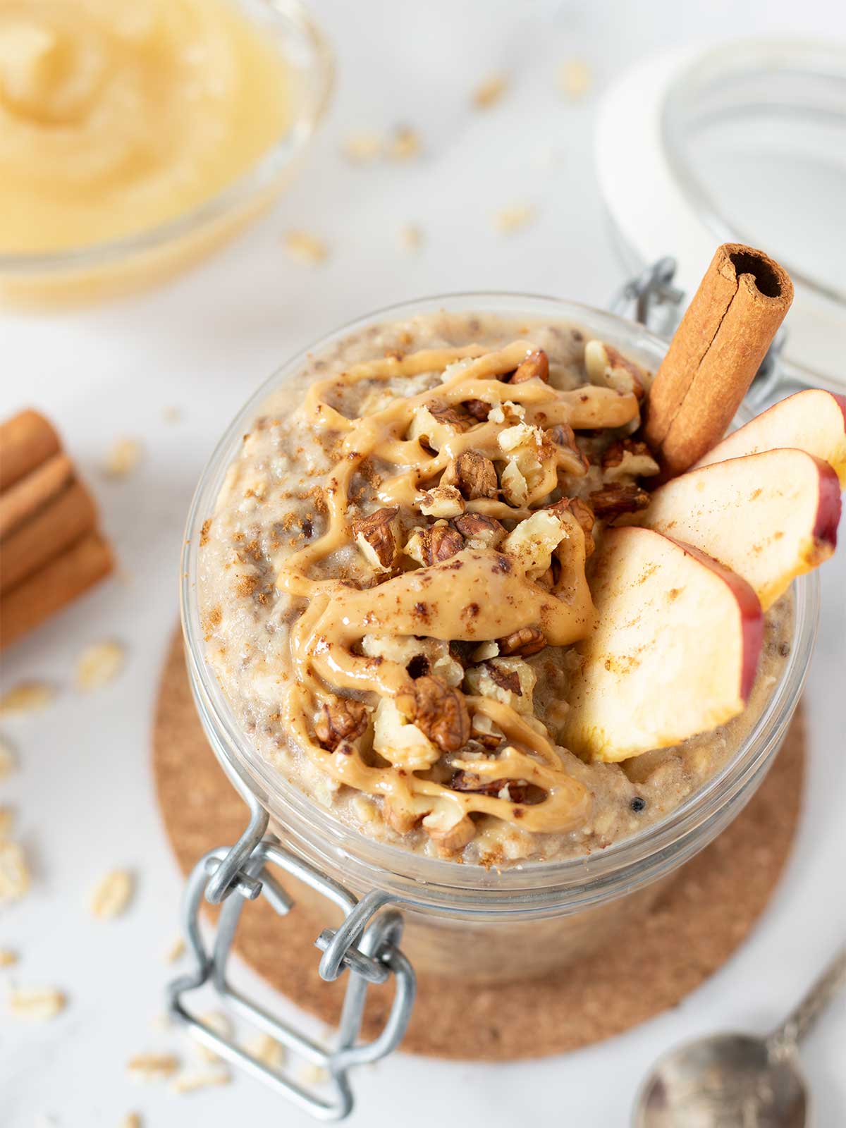 Vegan applesauce oatmeal in a jar with cinnamon, peanut butter, and walnuts.
