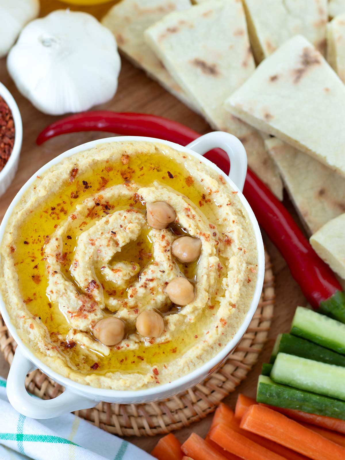 Homemade garlic hummus without tahini with fresh vegetables and pita bread.