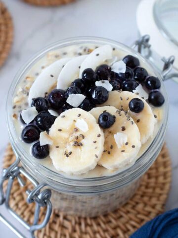 Overnight oats with water topped with chia seeds, banana slices, blueberries, and coconut flakes.