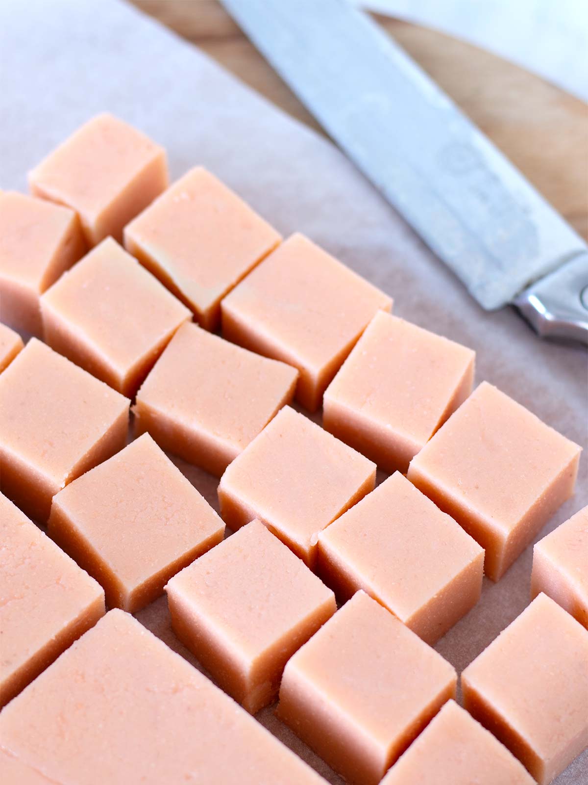 Homemade red lentil tofu cubes on a wooden cutting board with parchment paper.