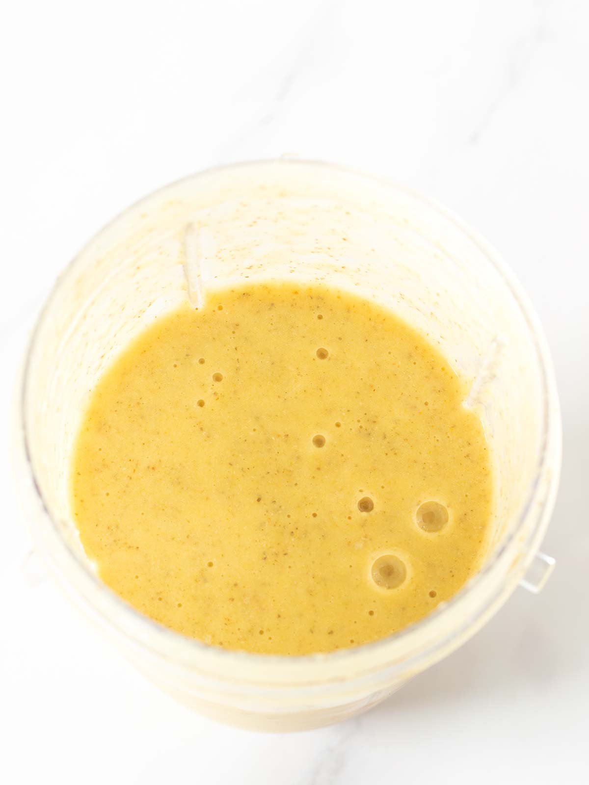 Creamy banana pineapple smoothie shake in blender cup.