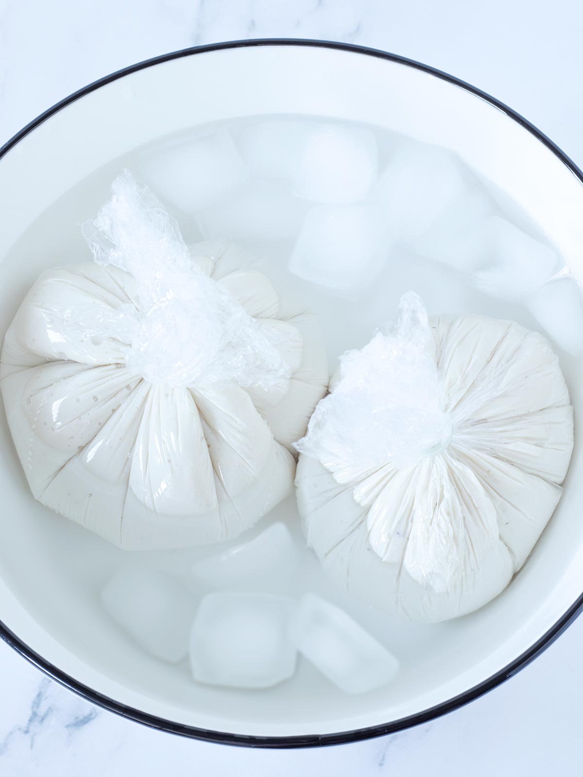 Plant-based cheese balls chilling in a bowl with ice cubes.