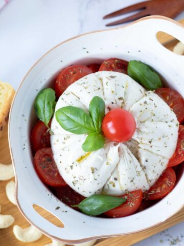 Vegan burrata cheese (dairy-free burrella) with cherry tomatoes, basil, and olive oil.