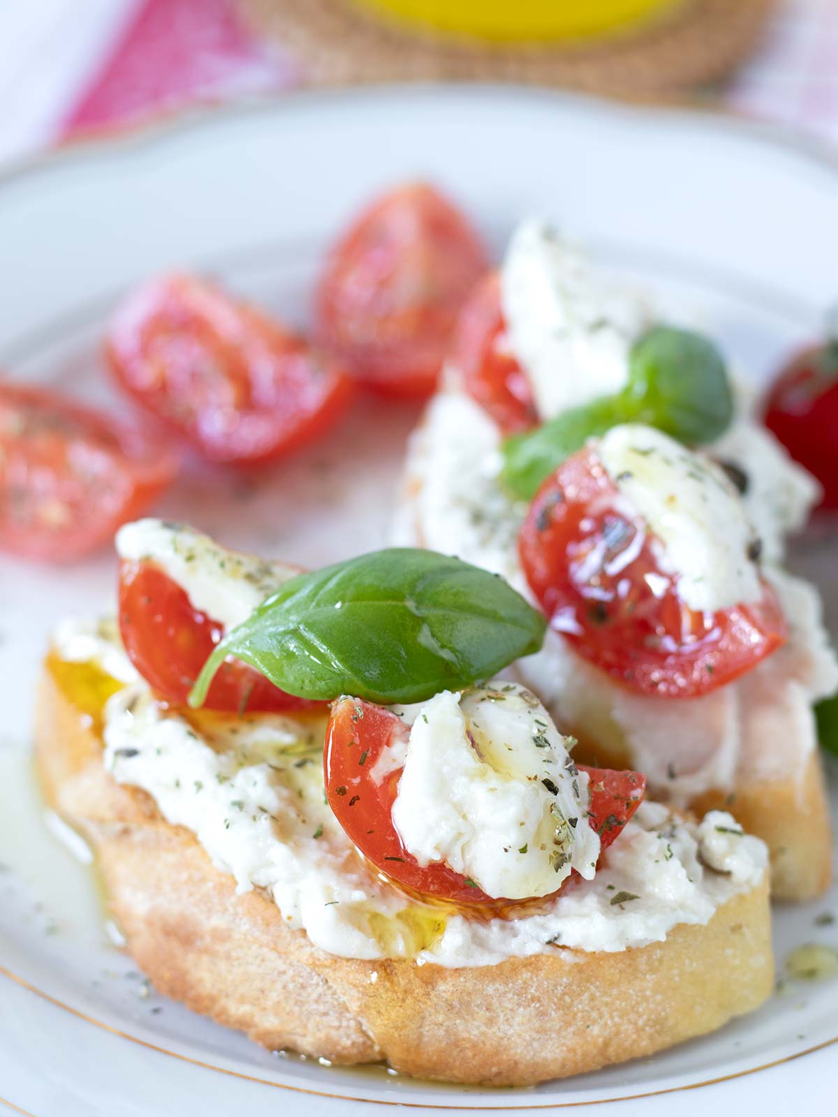 Homemade cashew-based burrata served on crusty bread with cherry tomatoes, basil leaves, and Italian seasoning.