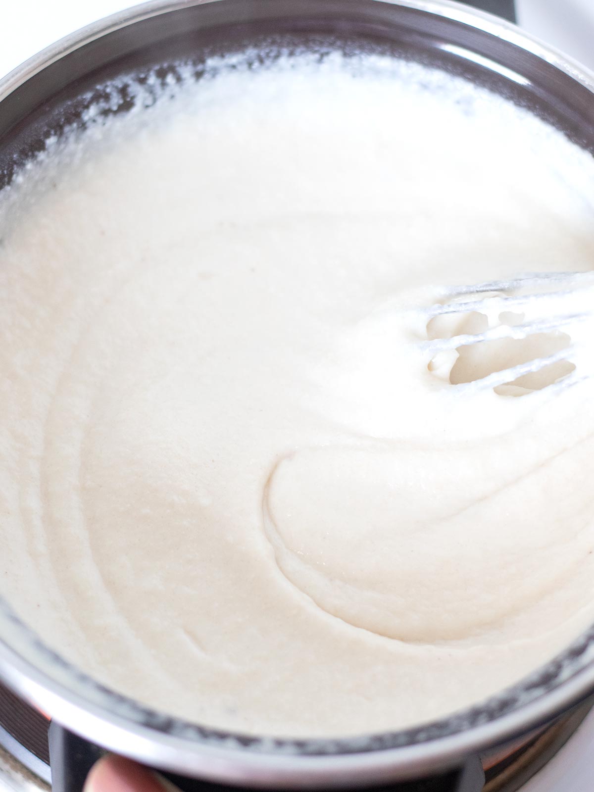 Cashew-based cheese mixture in a pot with a whisk.