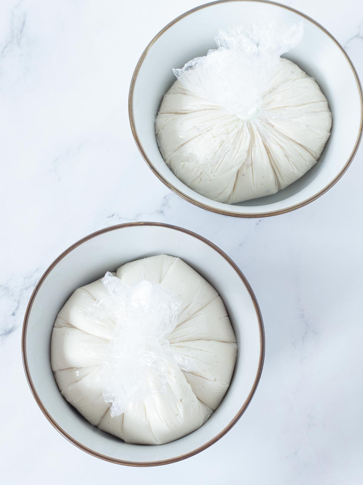 Vegan burrata cheese balls stored in two small bowls.