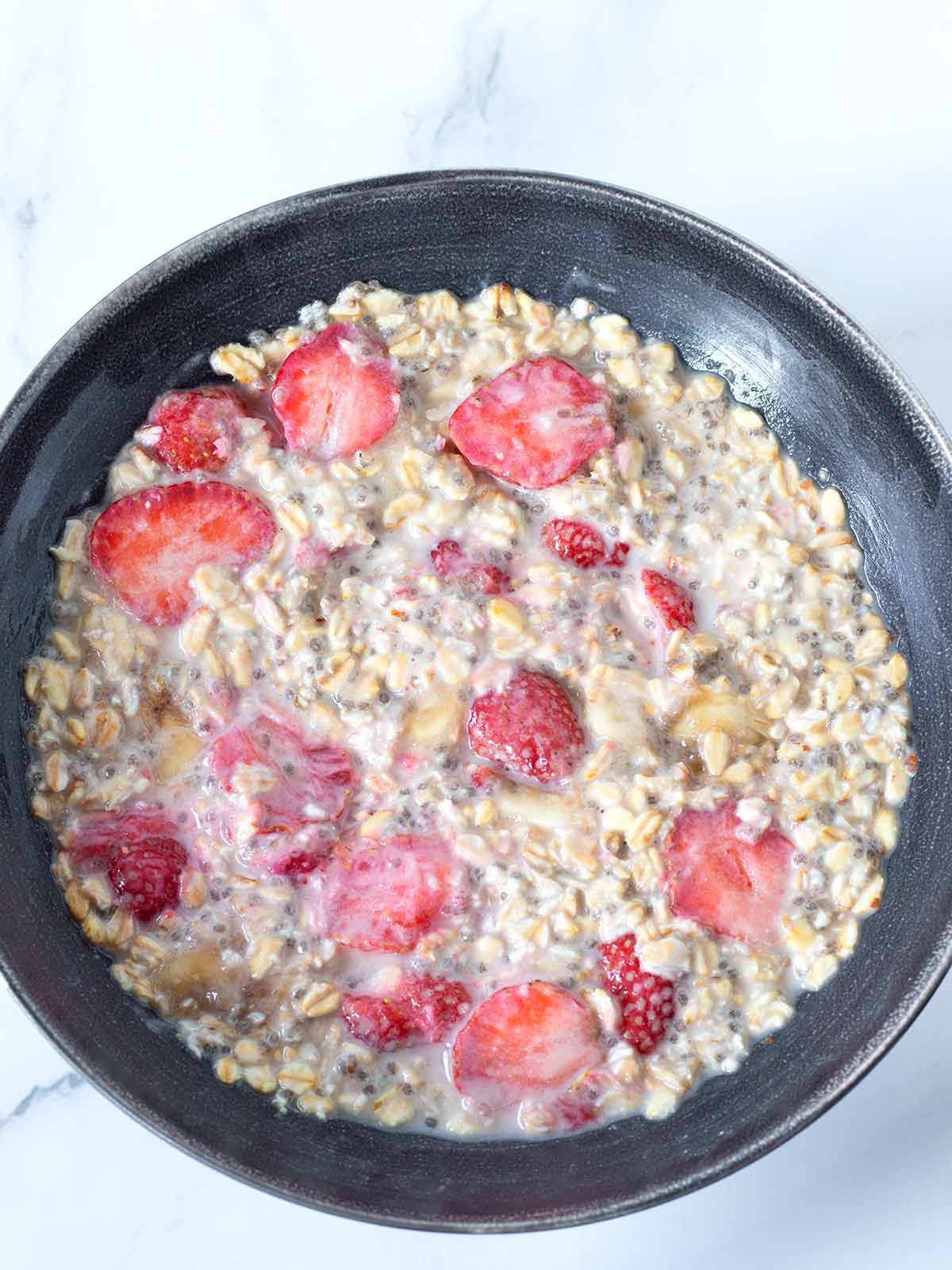 Creamy overnight oatmeal with fresh strawberries and bananas for breakfast.