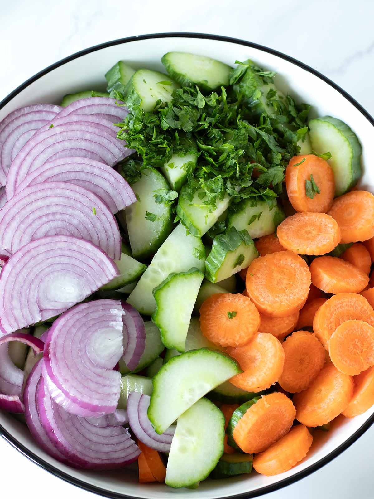Fresh chopped vegetables (cucumbers, carrots, red onion and parsley) for healthy vegan salad.