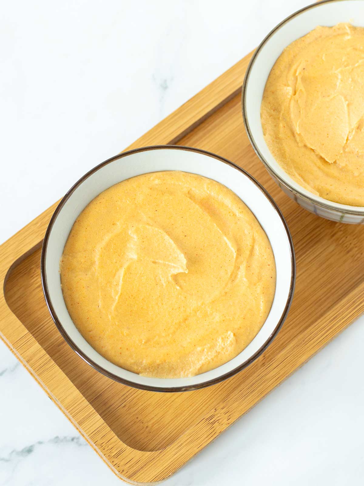 Healthy vegan cheddar cheese in round dishes prepared for chilling.