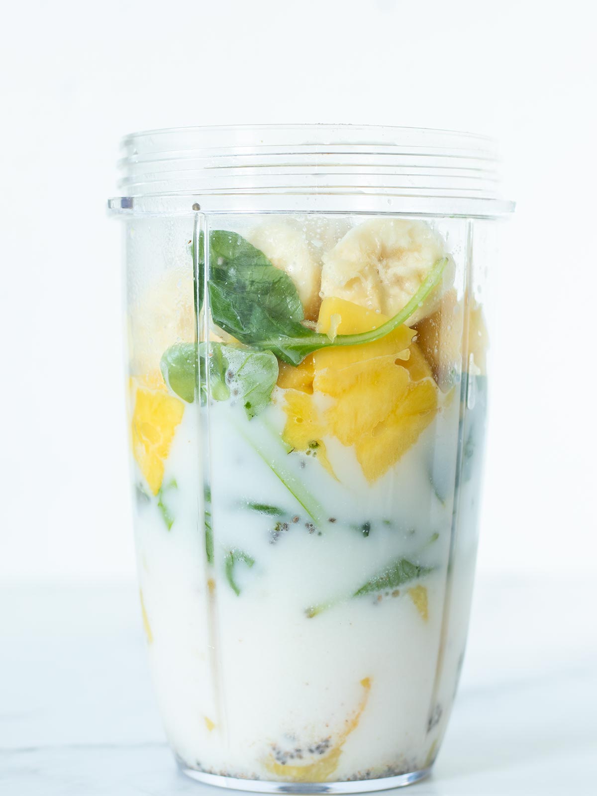 Pineapple mango spinach smoothie ingredients prepared for blending.
