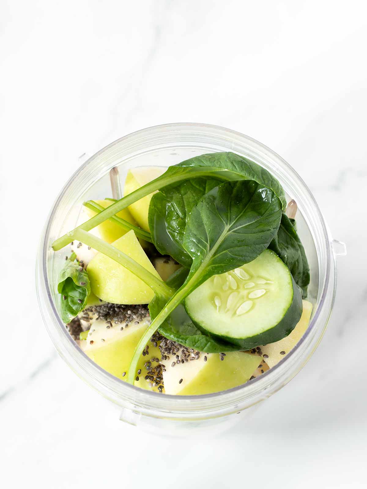 Cucumber spinach smoothie ingredients in a blender cup.