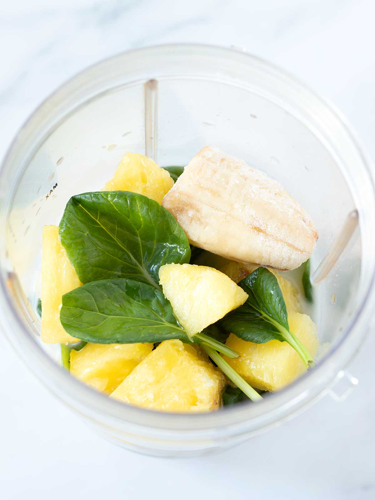 Green smoothie drink ingredients in blender cup.