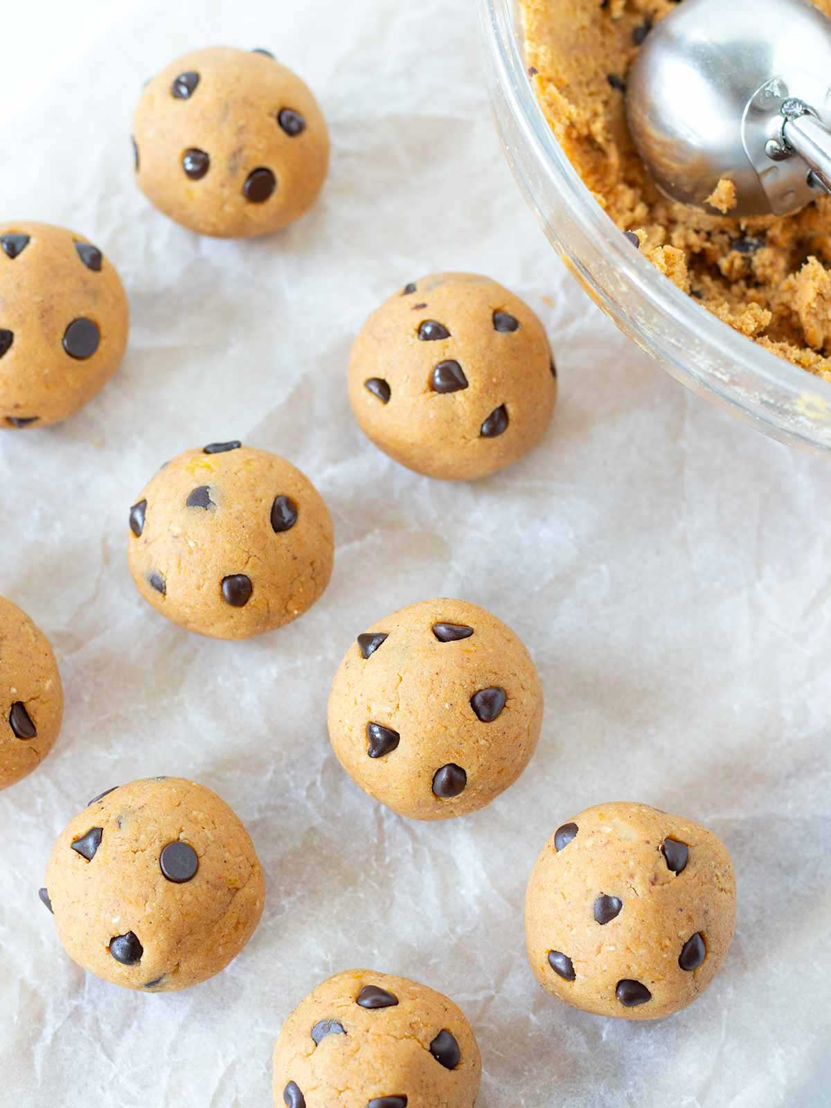 Rolling healthy no-bake pumpkin protein balls on parchment paper.