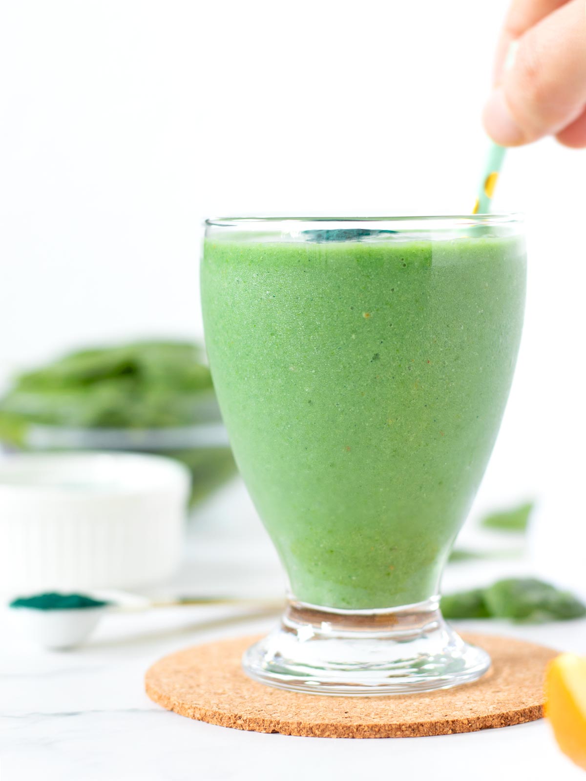 Green spirulina morning smoothie drink with banana, protein powder, spinach, avocado, pineapple, and orange juice.