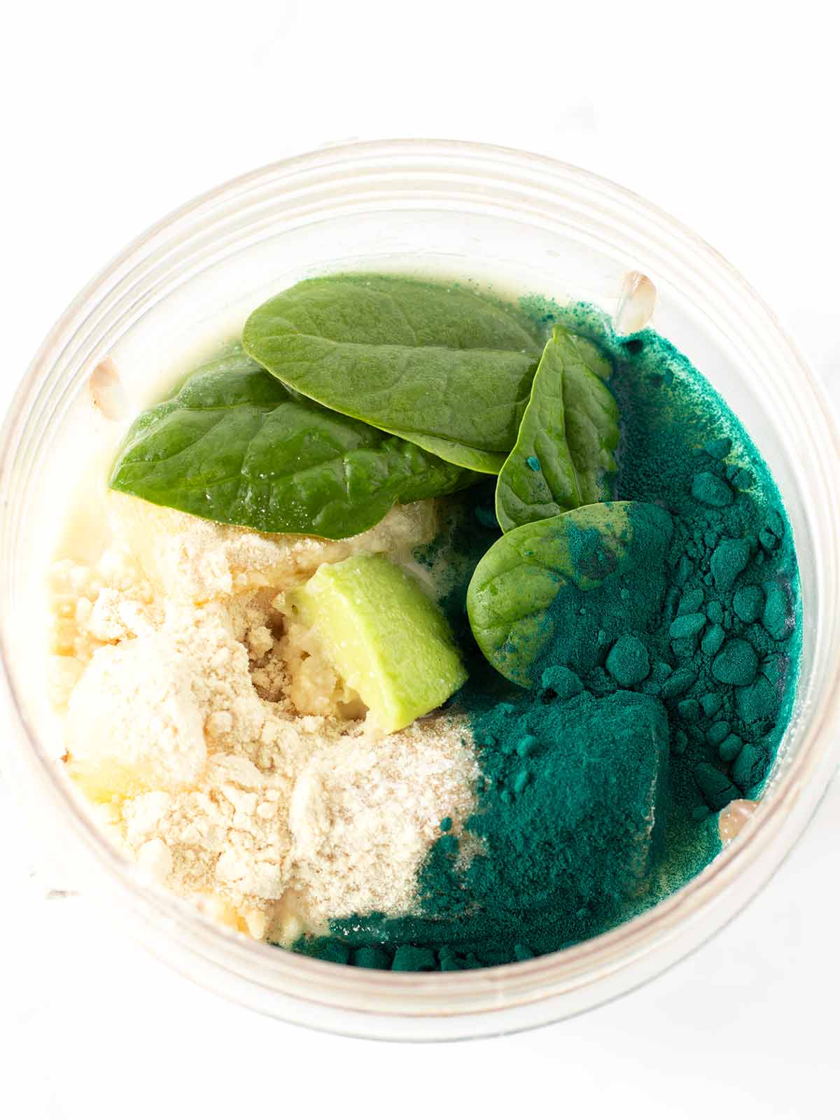 Green spirulina smoothie ingredients in blender.