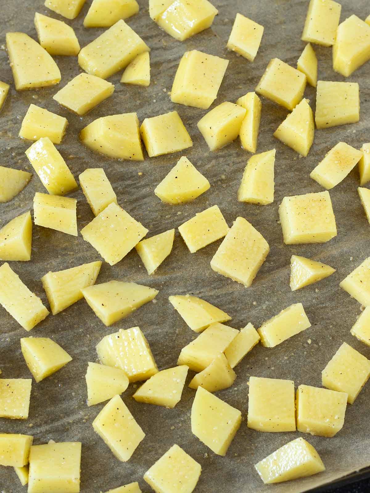Cubed potatoes with spices prepared for roasting.