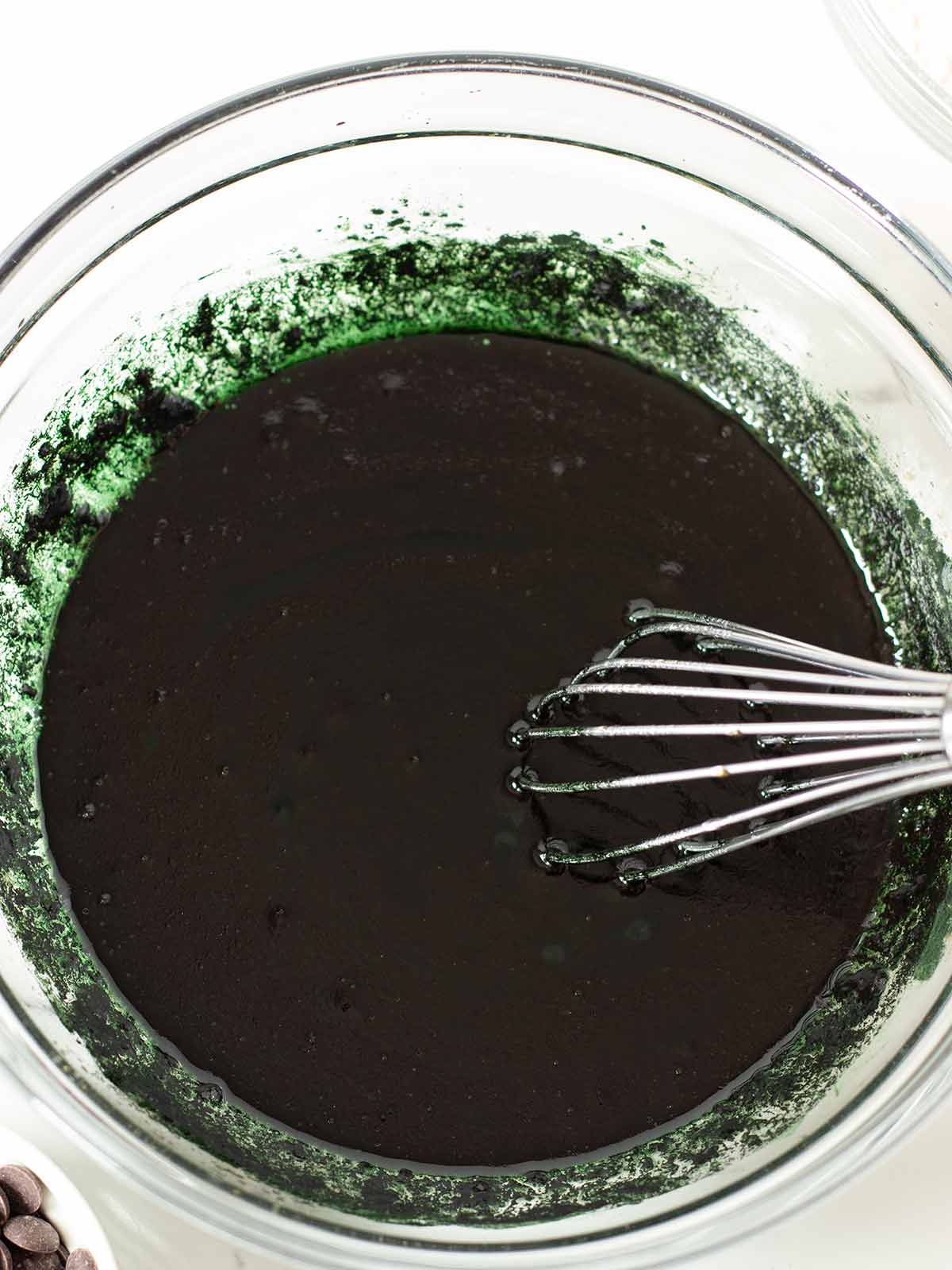 Green spirulina cookies batter in a bowl with a whisk.