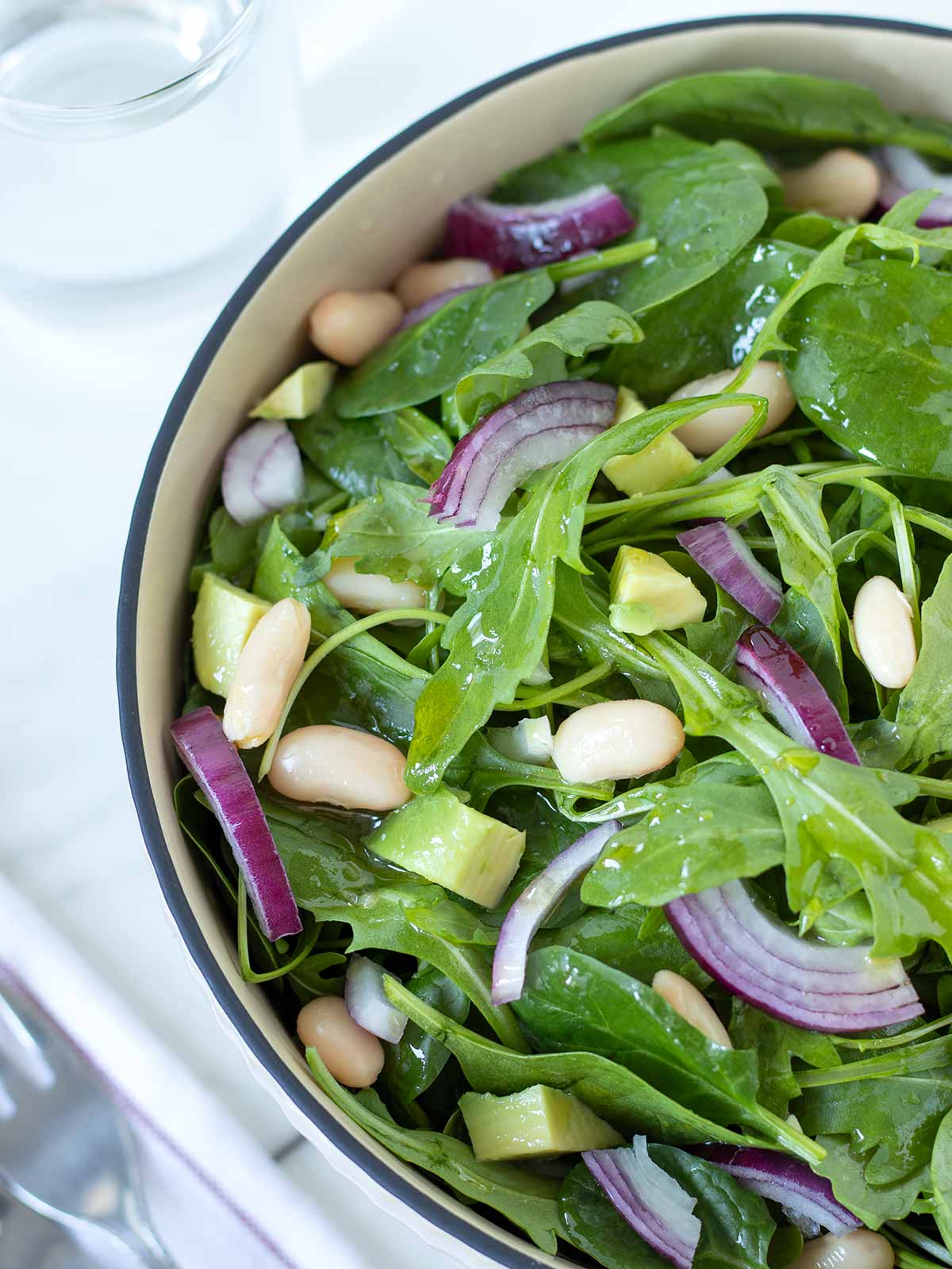 Spinach arugula salad with avocado and cannellini beans.