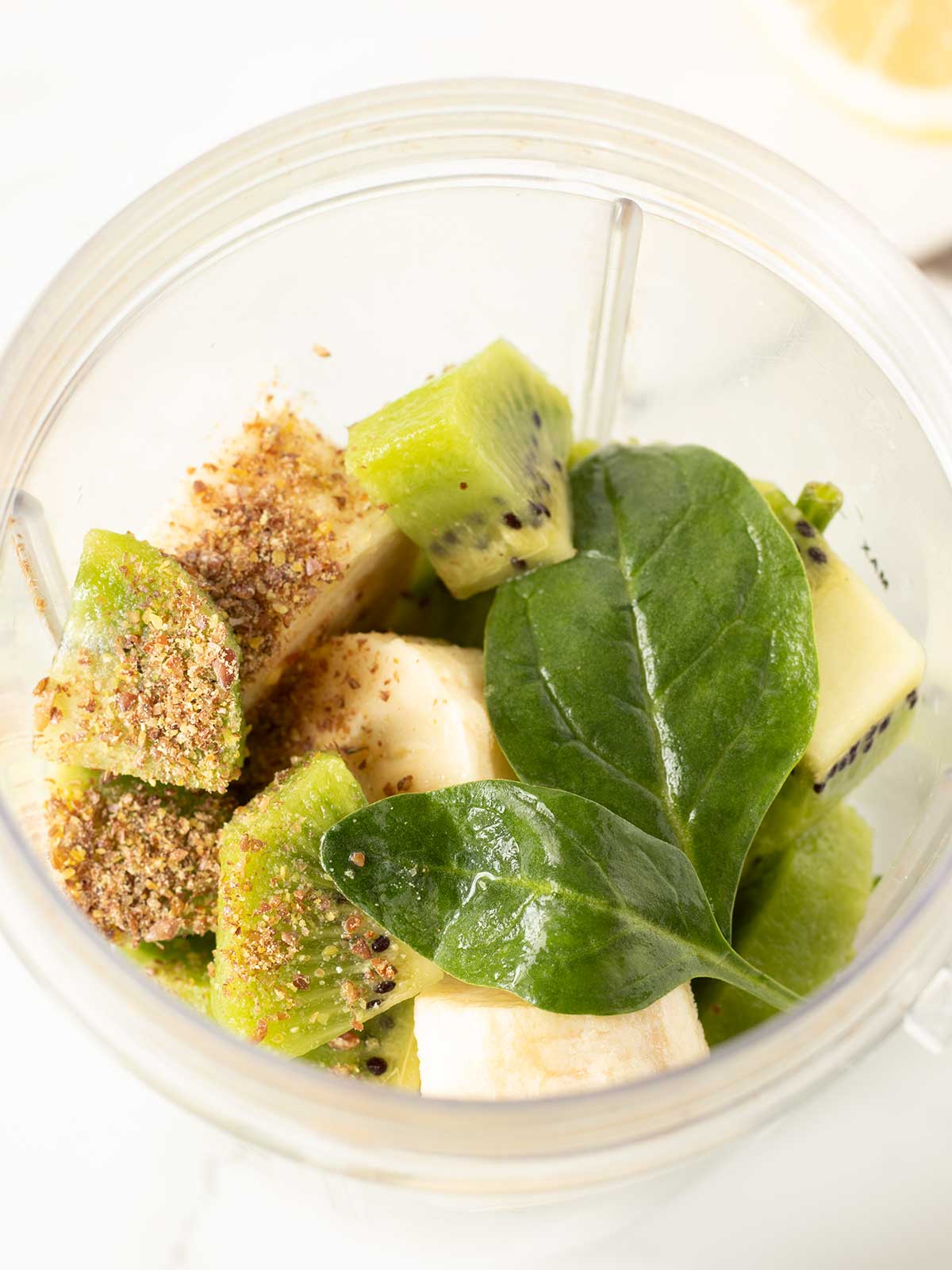 Banana kiwi spinach shake ingredients in a blender.