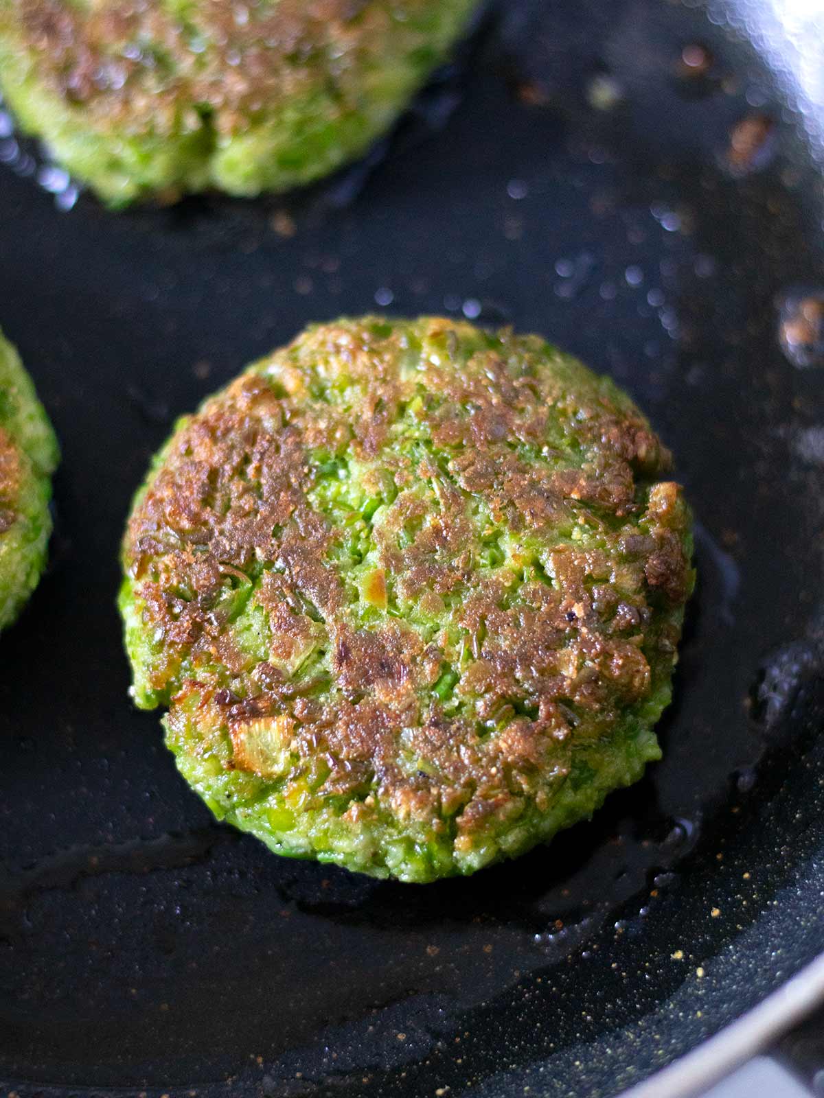 Gluten-free green pea fritters in a frying pan.