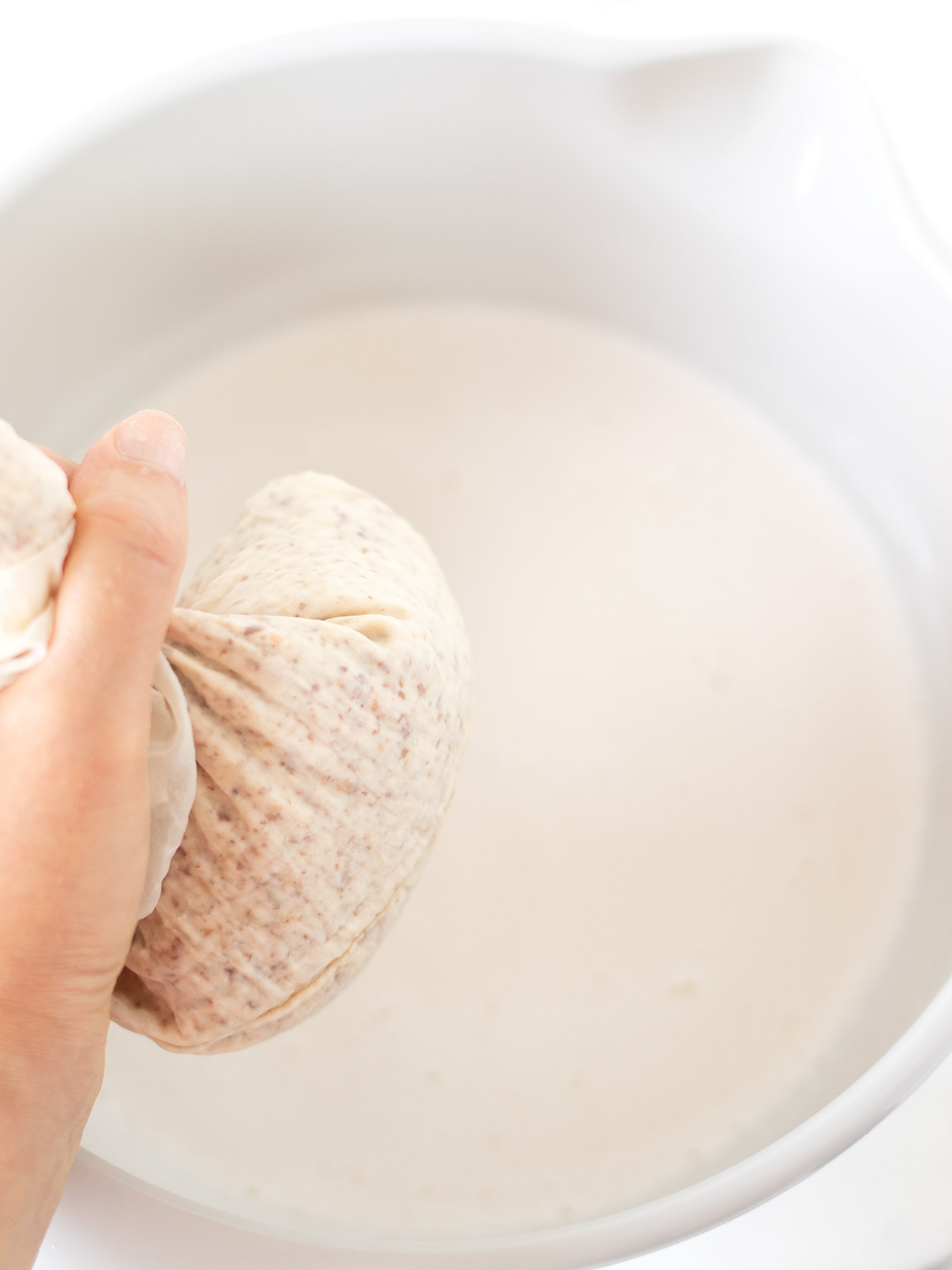Straining homemade almond milk with nut milk bag.
