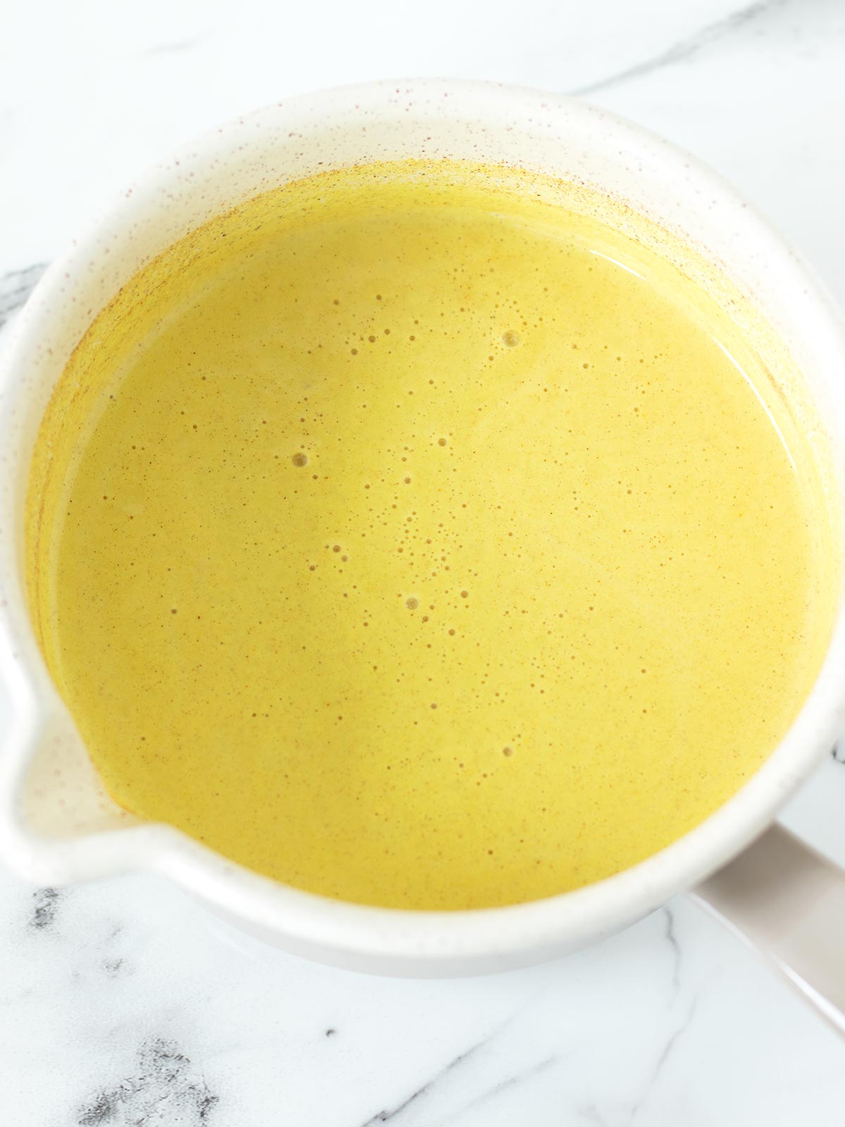Vegan turmeric golden milk latte in saucepan.