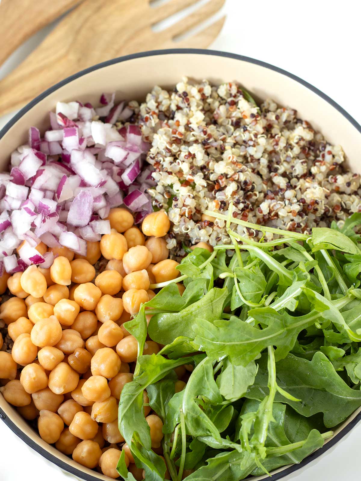 Arugula, quinoa, chickpeas, and red onion in a salad bowl.