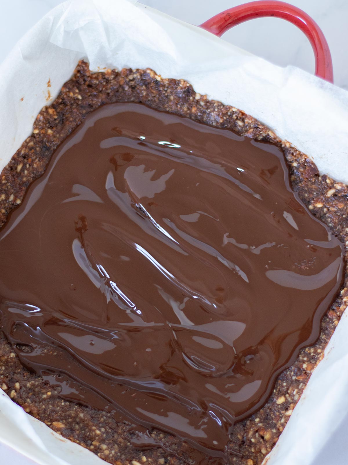 Melted dark chocolate on top of date nut bars.