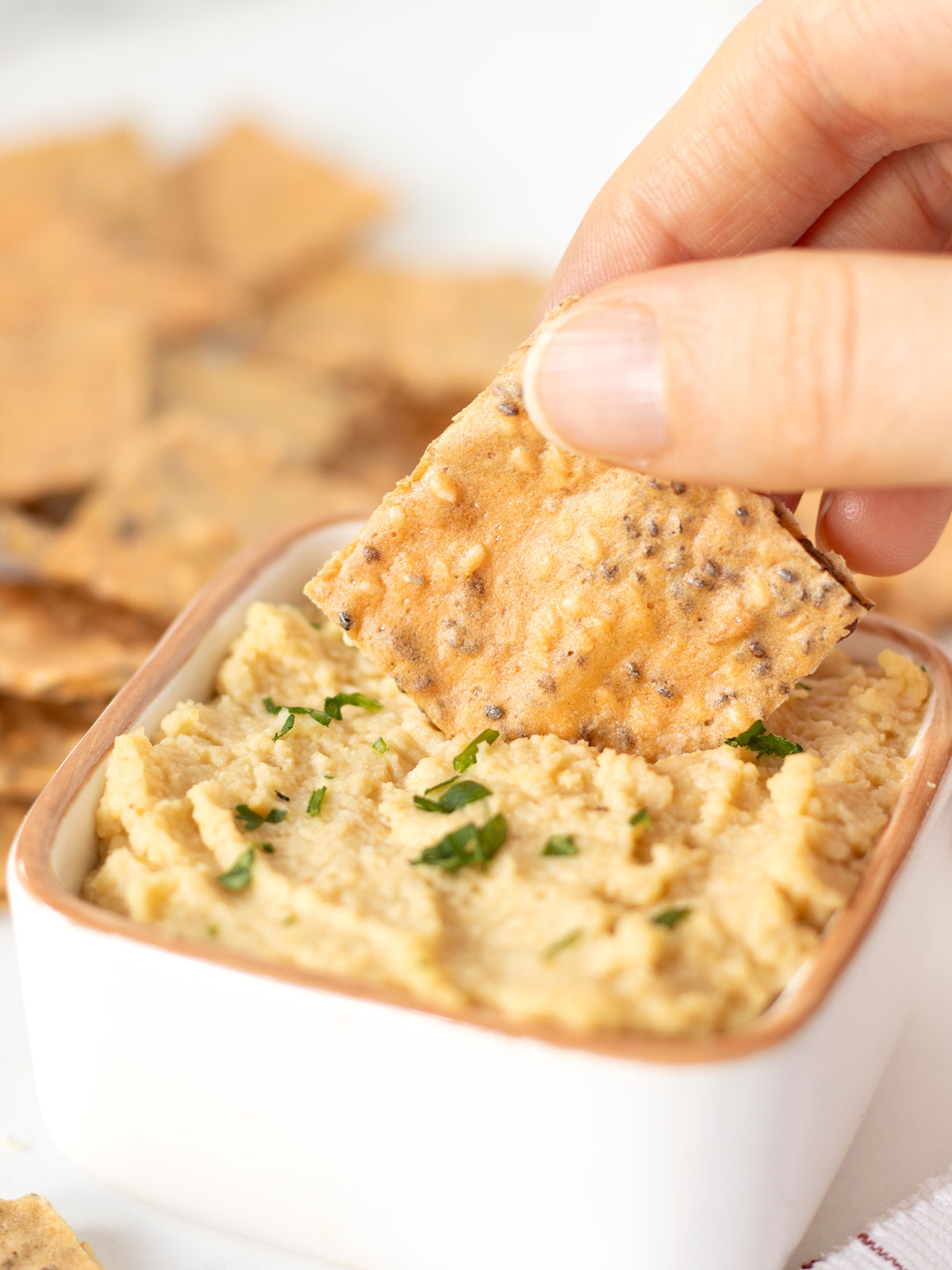 Dipping red lentil cracker in hummus.