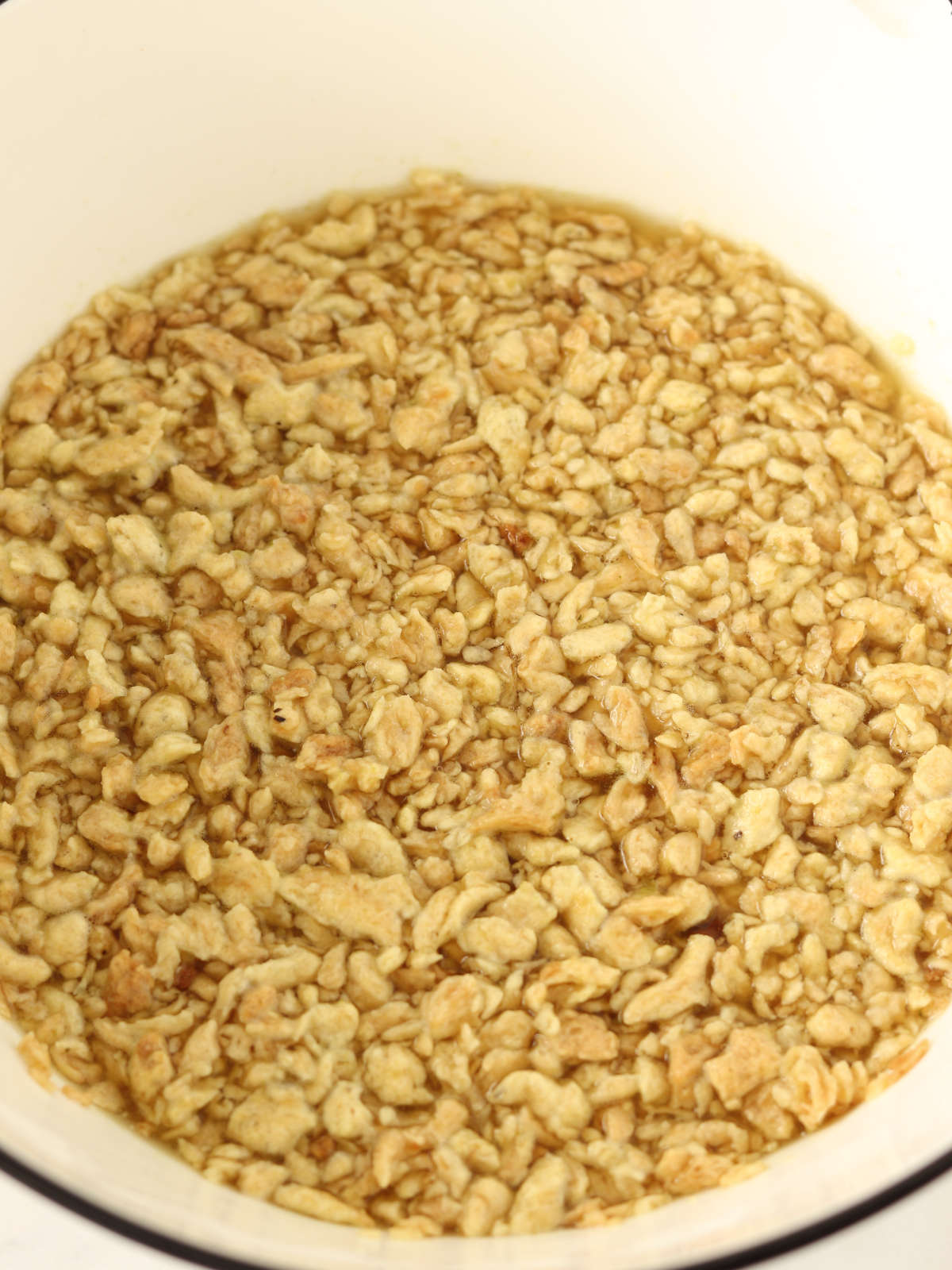Soy textured vegetable protein soaking in vegetable broth for vegan protein burgers.