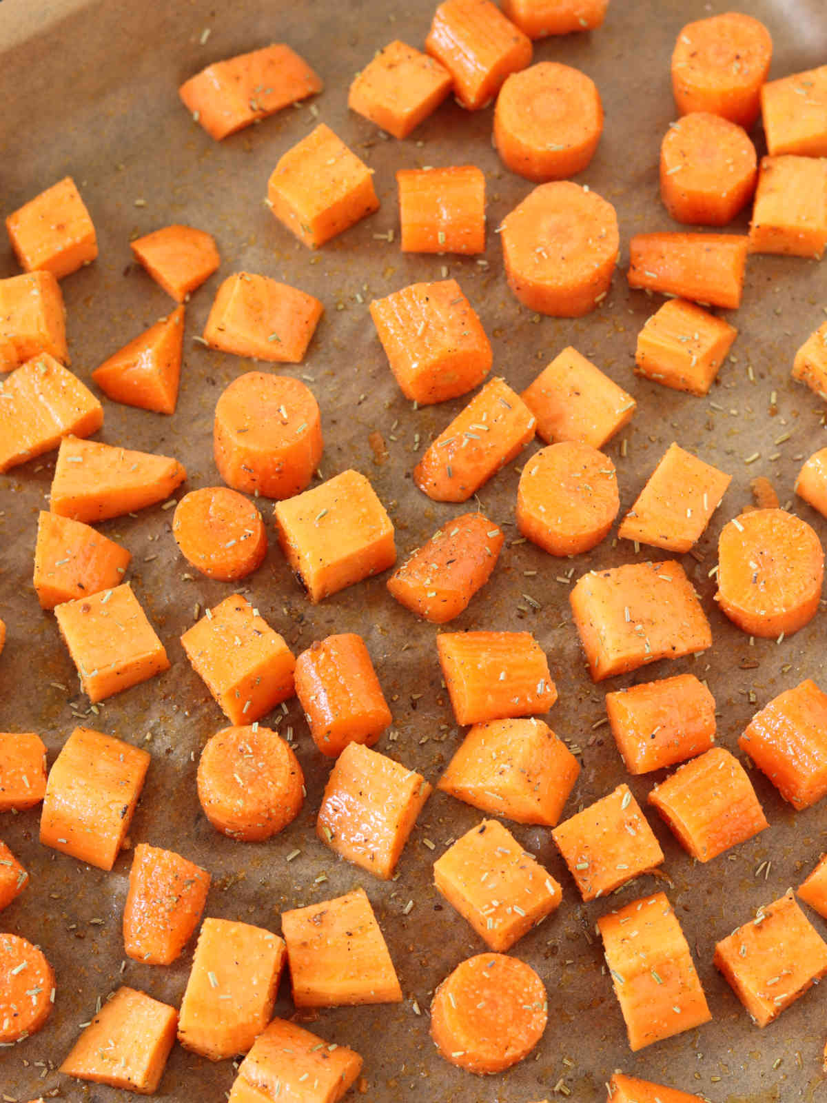 Sweet potatoes and carrots on baking sheet prepared for baking.