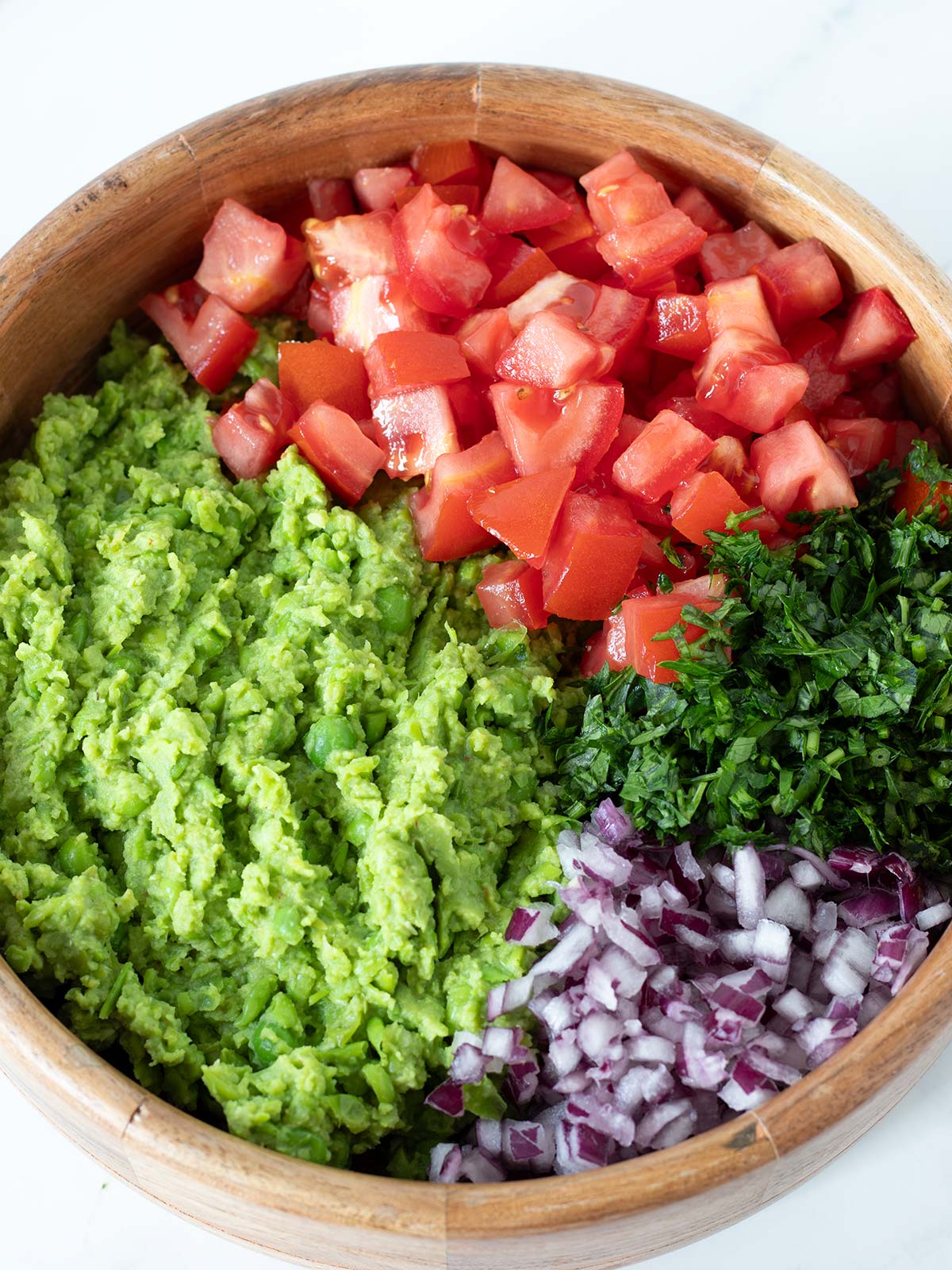 Green pea guacamole ingredients in a bowl.