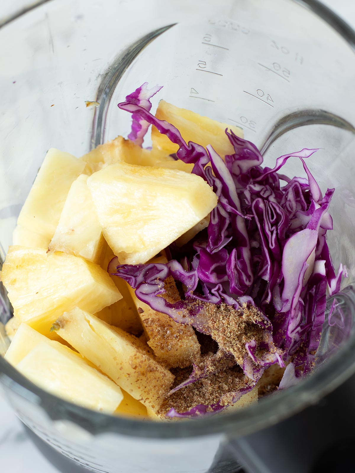 Red cabbage pineapple smoothie ingredients in a blender.