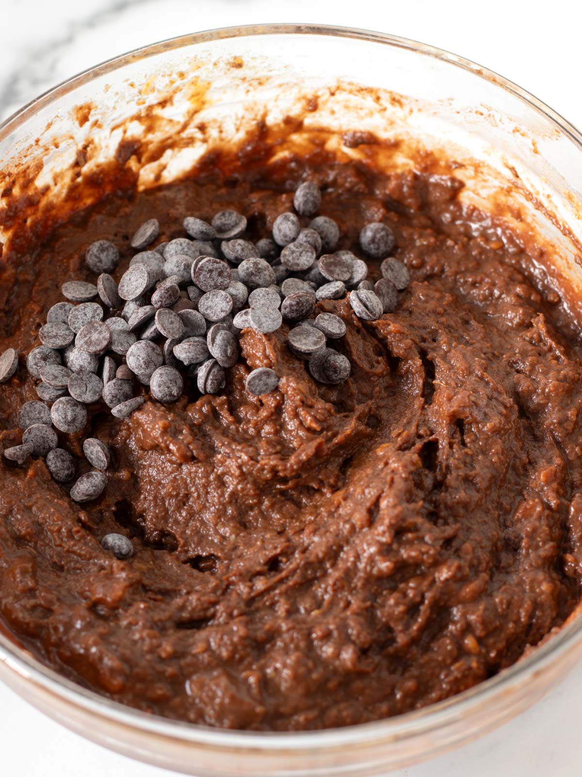 Chocolate chips on top of vegan sweet potato brownie batter.