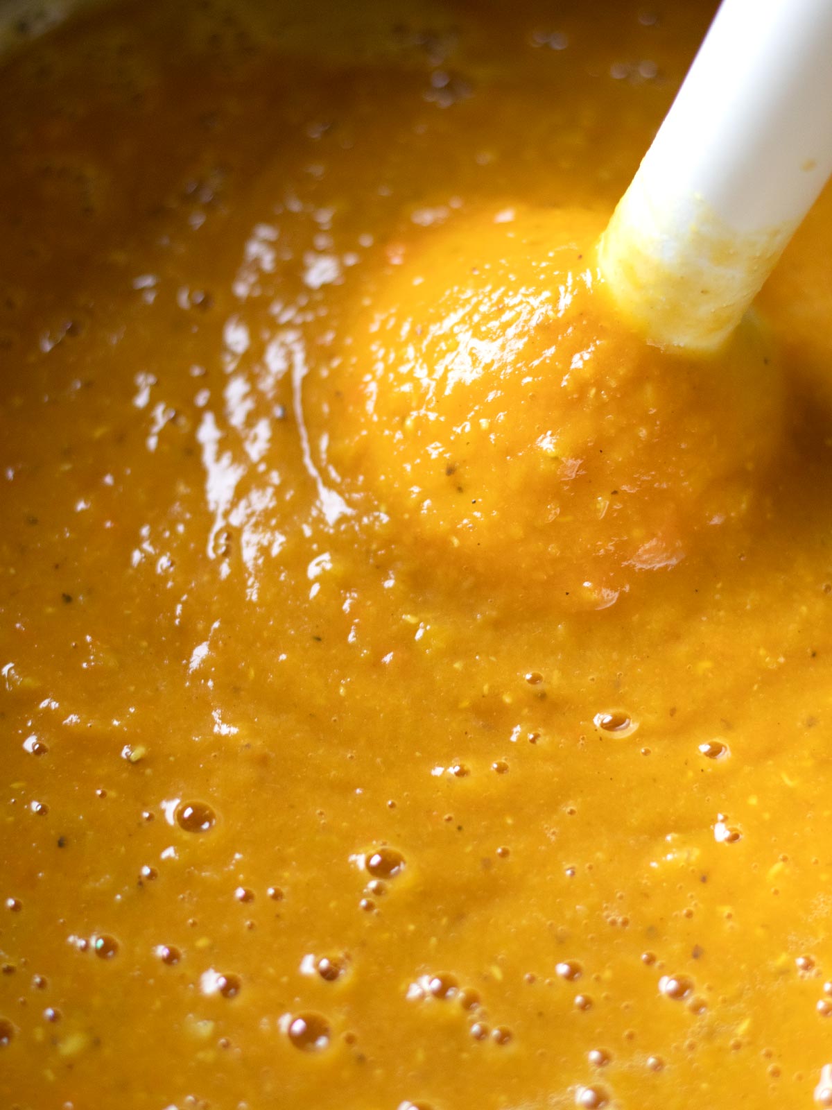Blending lentil sweet potato soup with immersion blender.