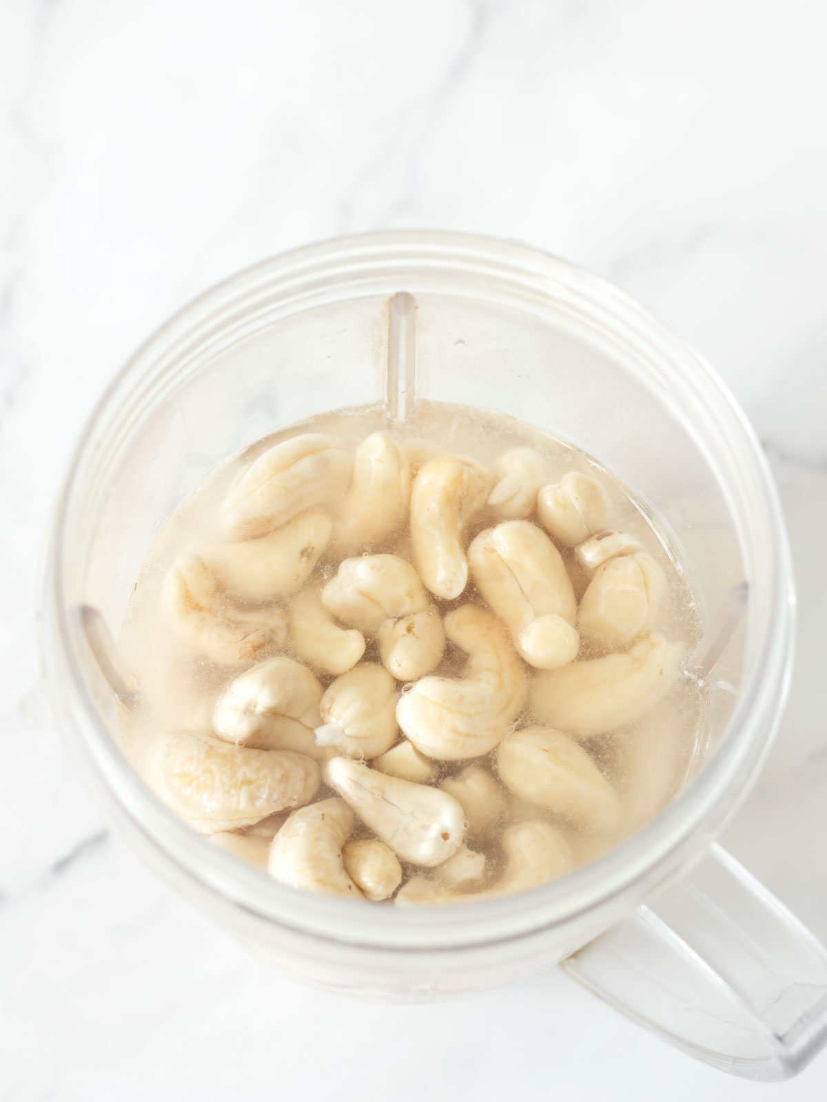 Ingredients for dairy-free cashews cream in a blender cup.
